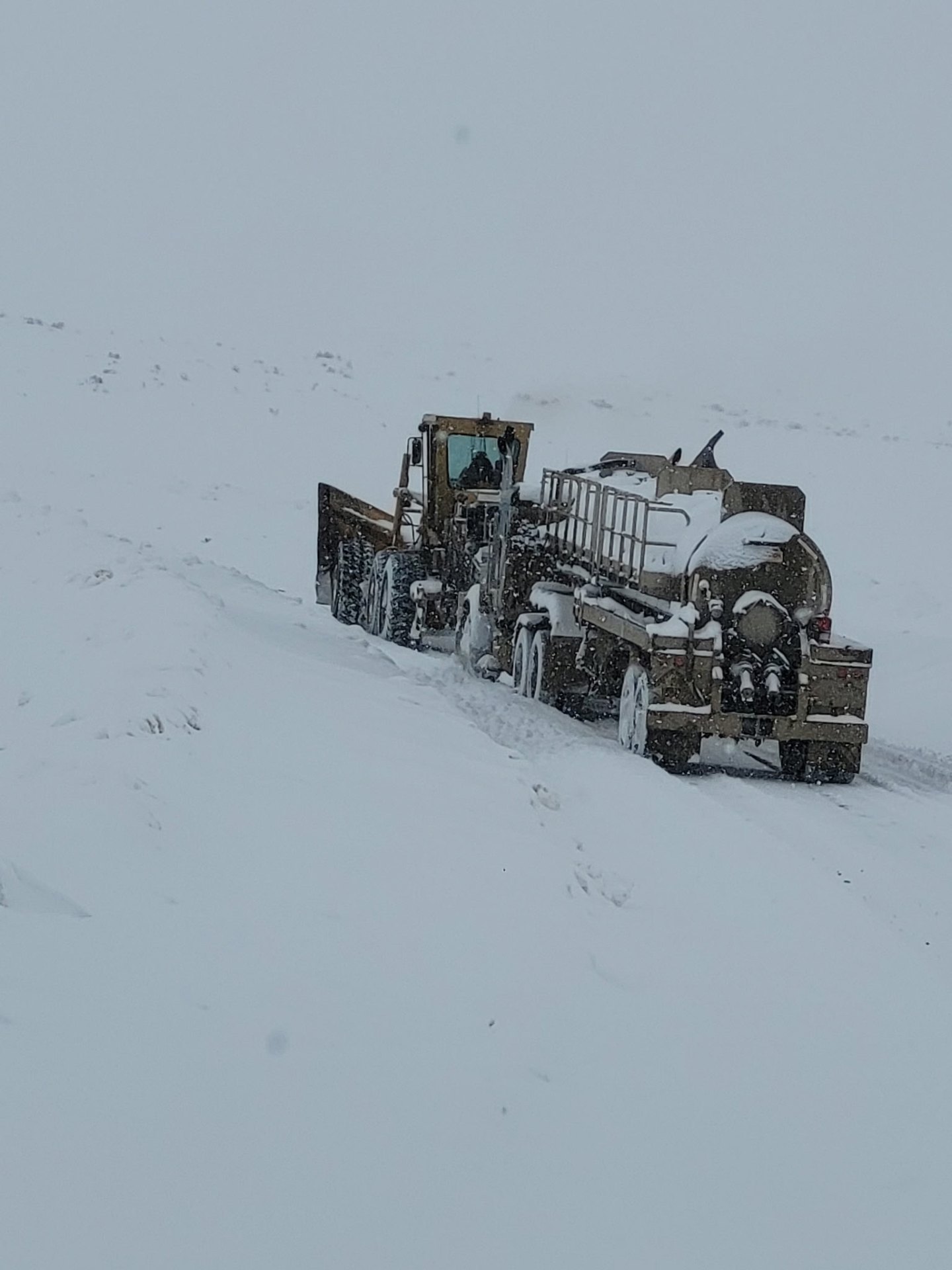 Motor grader and water truck working through a Wyoming snowstorm