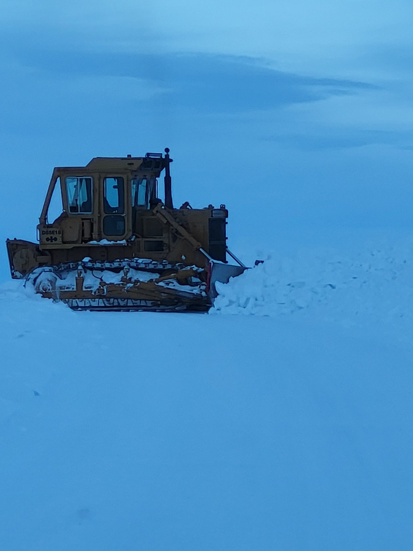 Komatsu dozer pushing snow on a winter Wyoming lease road