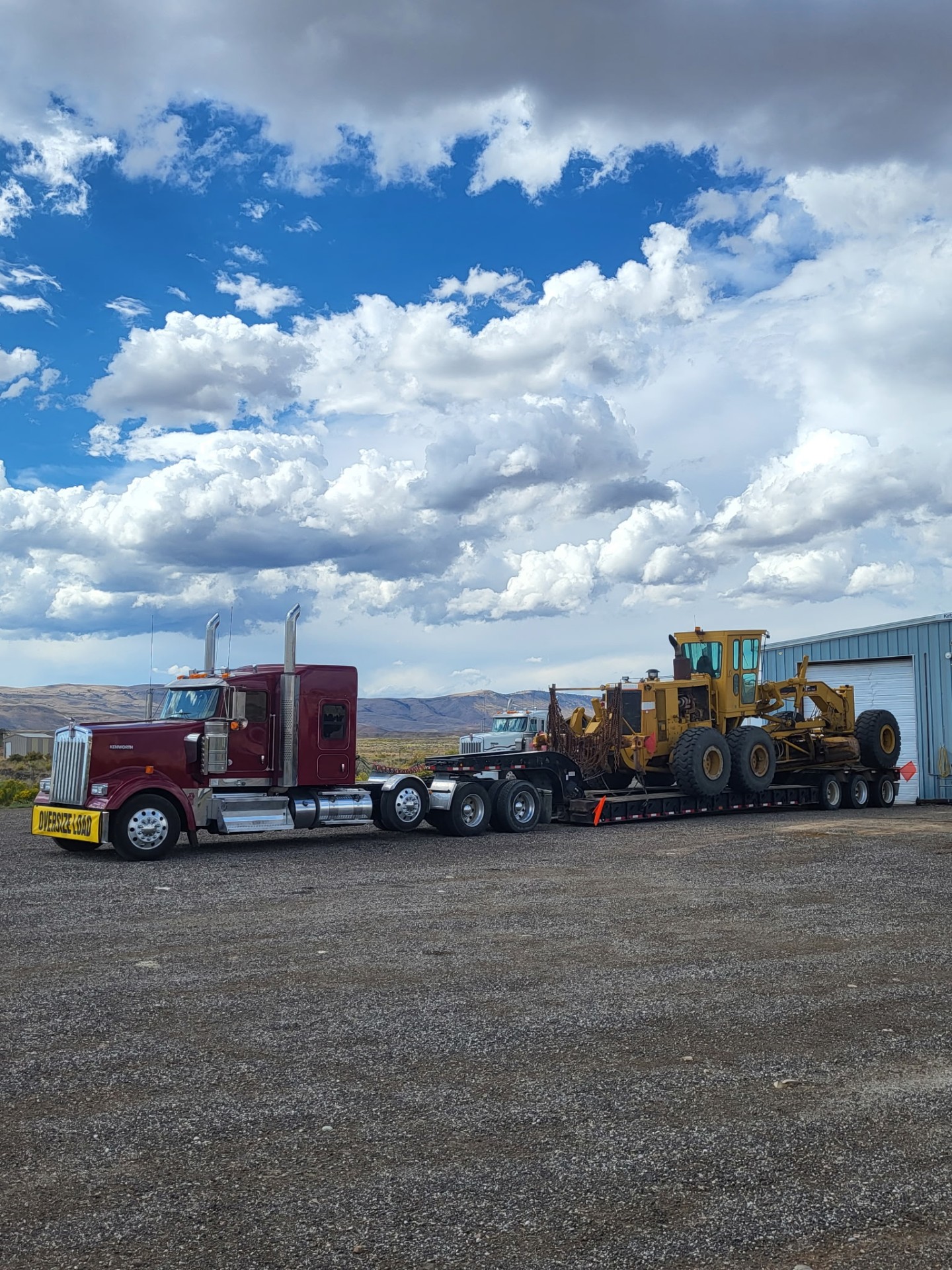 Kenworth oversize load hauling a motor grader on a lowboy trailer